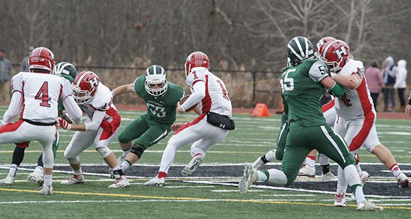 Brendan Delaney (7) clogs a hole and meets the Holliston quarterback on a scramble attempt up the middle. Photos by Paul Goldburg