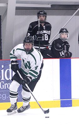 Sophomore Cal Guarino (14) defends as coaches and teammates look on.