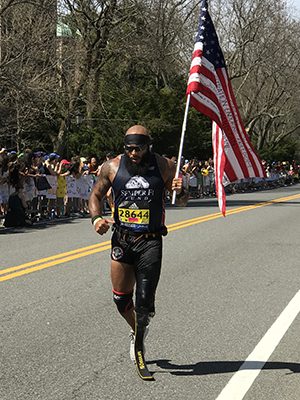 Jose Luis Sanchez, a Marine sergeant who lost a limb after stepping on an IED in Afghanistan, inspires onlookers as he carries the stars and stripes through Wellesley. Photos by Lisa Moore