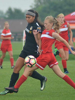 Maddi Peck (red) fights off a defender for a loose ball during NEFC’s 13-U national championship contest with California on July 18. Photos by Stacey Herman