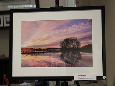 Chuck Ferullo’s 'Purple Sunrise, Flooded Charles' captures a breathtaking sunrise, as pinks, purples, and yellows streak across the sky and are reflected by the water.