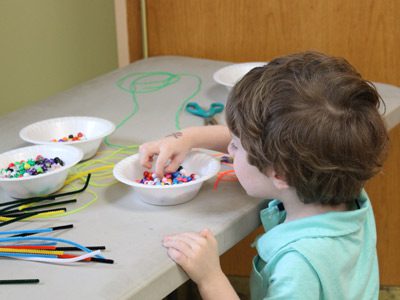 Three-year-old Lior sifts through a bowl of beads to find the perfect ones for the necklace he was making for his mom.