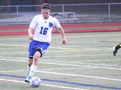 Senior captain and forward Corey Lampman (16) gathers in a ball and rushes up the field for DS midway through the second half.