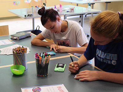 A group of seventh graders focus on their button designs before starting on the day’s homework at the Westwood Library’s ‘Half Wednesday Hangtime.’ Photos by Laura Drinan