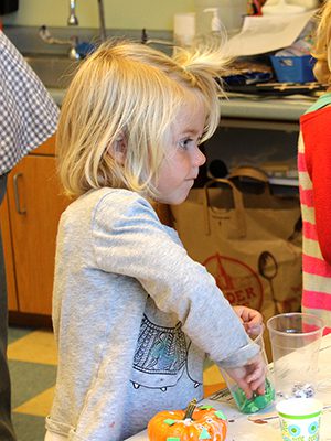 Two girls decorate miniature pumpkins with a slew of craft supplies at Susan’s Surprise K to First Grade Fun at the Medfield Public Library.