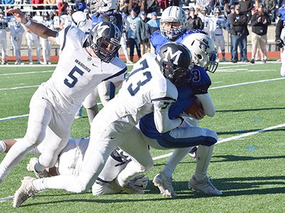 DS quarterback and captain Holden Ferrari (3) tries to escape the grasp of Medfield’s Andrew Cook (73) with support from Mitchell Gonser (5) about to arrive. Photos by Lizzy Collotta