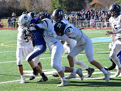 DS running back Timothy Polk (4) attempts to break through a gang of Medfield tacklers that includes senior captain and defensive end John Lowell (77), junior defensive end Daniel Dealy (48), and senior captain and defensive back Ben Adams (20). Photos by Lizzy Collotta