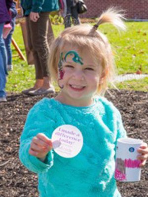 A Full Circle participant proudly displays her ‘I made a difference today’ sticker and the donation jar she decorated.