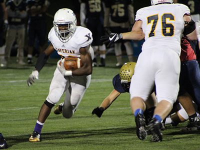Xaverian running back Ikechukwu Irabor (20) dashes up the middle through a gapping hole set up by senior right tackle Grant Laws (76) early in the first quarter of Friday night’s 28-0 South Semifinal win at Needham. Photos by Michael Flanagan