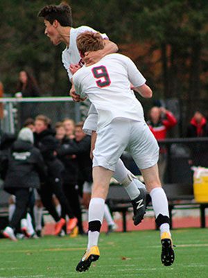 Danny Frei (11) celebrates his a goal 15 minutes into the game with teammate Brendan Clare (9) as the Raider sideline enters a state of pandemonium in the background.