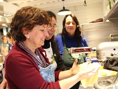 Mary, a participant at Powisset Farm’s Italian cooking class, rolls out pasta dough with COA directors, Lina Arena-DeRosa and Janet Claypoole. Photos by Laura Drinan