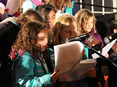 A group of Girl Scouts and Brownies perform classic Christmas carols for Needham’s Blue Tree lighting event. Photos by Laura Drinan