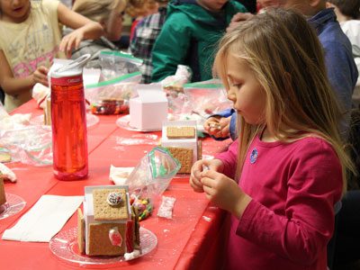 Five-year-old Collette Beasley decorates her gingerbread house with candies and icing at the Dover Town Library.