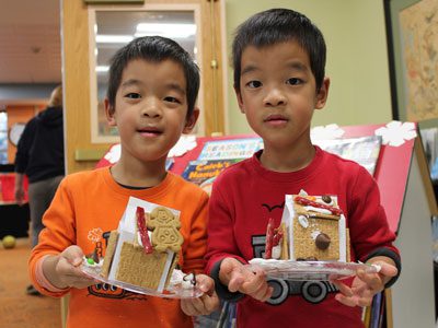 Four-year-old brothers Matthew and Nathan enjoy their decorated gingerbread houses that they created at the Dover Town Library.