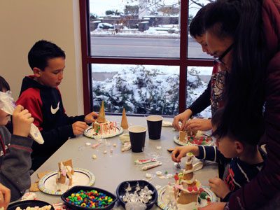 Several of the children at the Wellesley Library’s gingerbread house decorating event use ice cream cones to add height to their cookie houses.