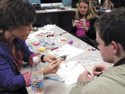 Bri Ozanne from the Medfield Public Library offers her experience with ceramics at the teen ornament-making event.