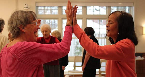 Seniors participate in a laughter activity at the Council on Aging, where they are instructed in roar with laughter as they high five. Photos by Laura Drinan
