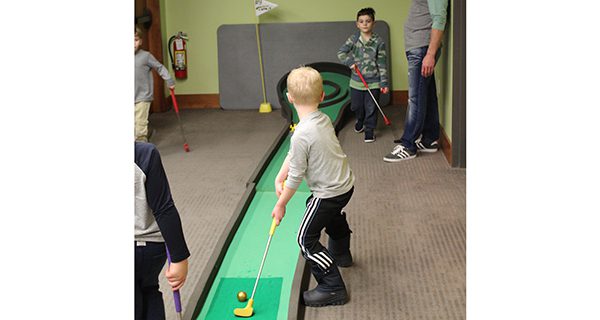 Children step up to the challenge of the skee-ball-inspired course at the library’s mini-golf event. Photos by Laura Drinan