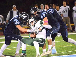 Three Warriors, Mason Giunta (33), John Lowell (77), and Elliott Mantz (81), bring down Westwood’s Jake Antonucci in Medfield’s final regular-season conference game of 2017. Photos by Elizabeth Collotta
