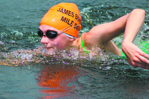 A swimmer makes her final break towards the finish during the girls heat of Friday’s Jim Ehrlich Mile Swim at Dug Pond in Natick.
