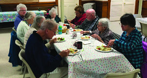 Senior citizens eat and socialize at the weekly luncheon at the Pilgrim Church.
