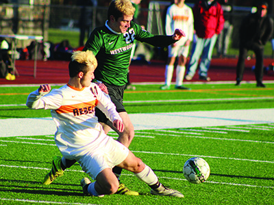Walpole’s Mike DiCenzo (11) performs a slide tackle on Westwood’s Eamon Doherty (22) late in the first half. Photos by Michael Flanagan