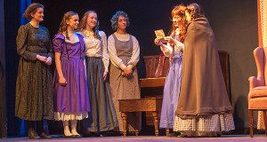 Marmee (Olivia Barrows), Amy (Jenna Eiten), Meg (Margo Memmott), Hannah (Arden Caldicott), Jo (Charlotte Buehler), and Beth (Claire Whitaker) gather around a letter in Little Women.