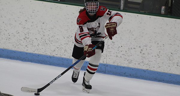 Junior defenseman Erin Fleming (19) moves the puck from behind her cage on the breakout. Photos by Michael Flanagan