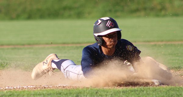 Bryce Anderson (pictured) slides safely into third base with a steal before coming in to score the second run of the game for Needham. Photos by Mike Flanagan