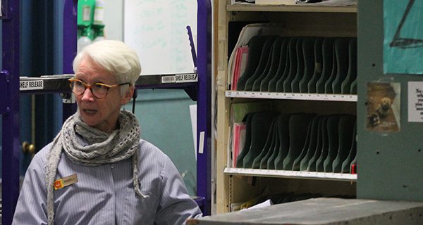 Tour guide Pamela answers a question in front of a mail carrier cubicle, where every slot would represent an address.